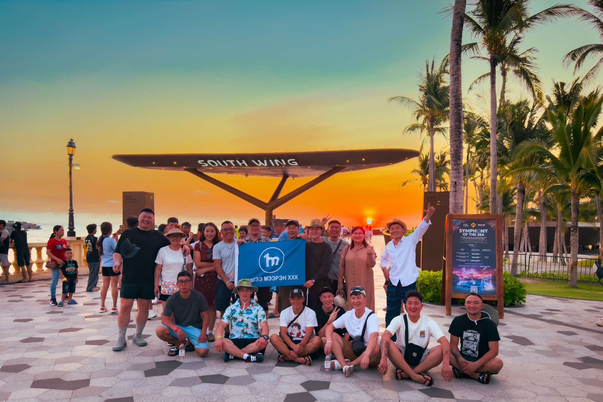 The Tushee Meeren team holding the company flag at a seaside sunset